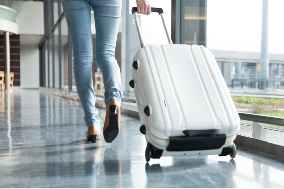 スーツケースを持って空港を歩く女性の足元の写真